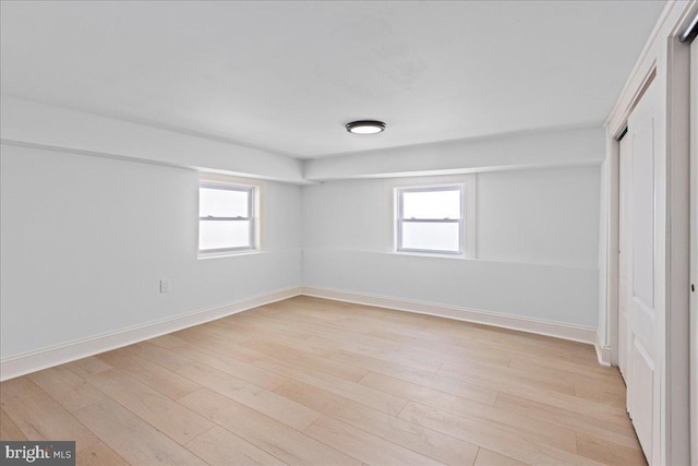 unfurnished bedroom featuring light wood finished floors, multiple windows, baseboards, and a closet