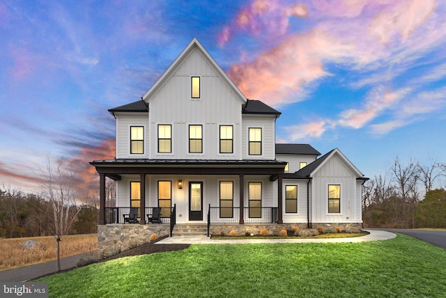 modern farmhouse with metal roof, a standing seam roof, a porch, board and batten siding, and a front yard