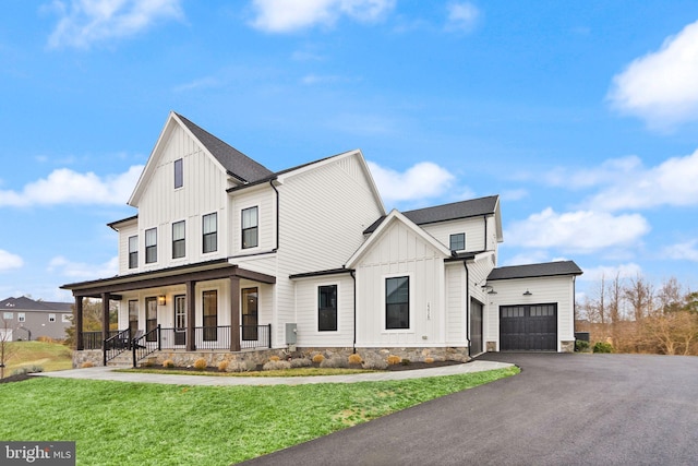 modern farmhouse featuring aphalt driveway, a porch, board and batten siding, a front yard, and a garage