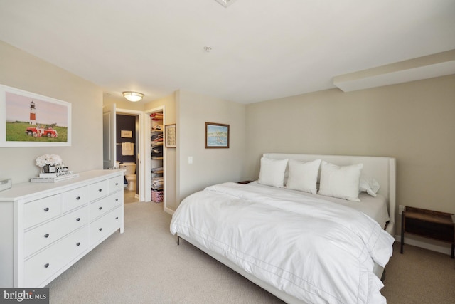 bedroom with a closet, light colored carpet, and a spacious closet