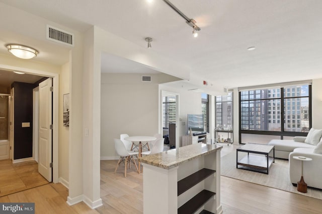 kitchen with open floor plan, visible vents, light wood-style flooring, and light stone countertops