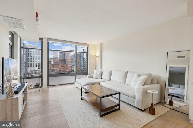 living room with a city view, visible vents, and light wood-style floors