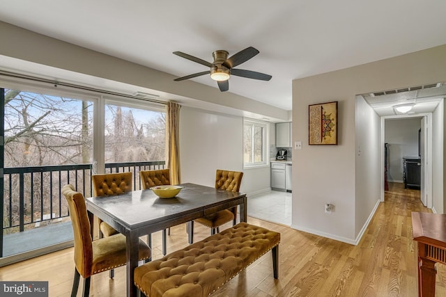 dining room featuring light wood finished floors, baseboards, visible vents, and a ceiling fan