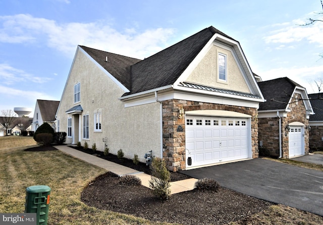 view of side of property featuring a garage, driveway, metal roof, a standing seam roof, and stucco siding