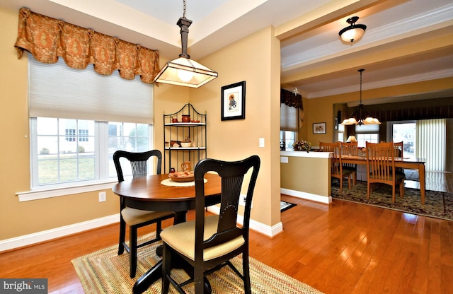 dining room with a notable chandelier, baseboards, wood finished floors, and ornamental molding