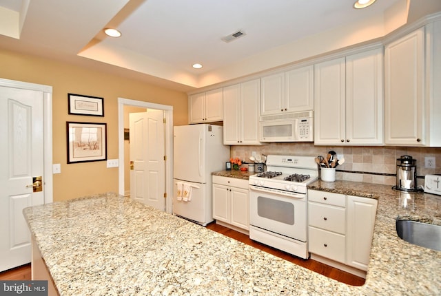 kitchen featuring white appliances, visible vents, a raised ceiling, decorative backsplash, and recessed lighting