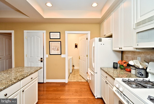 kitchen with tasteful backsplash, white appliances, light wood-style flooring, and white cabinets