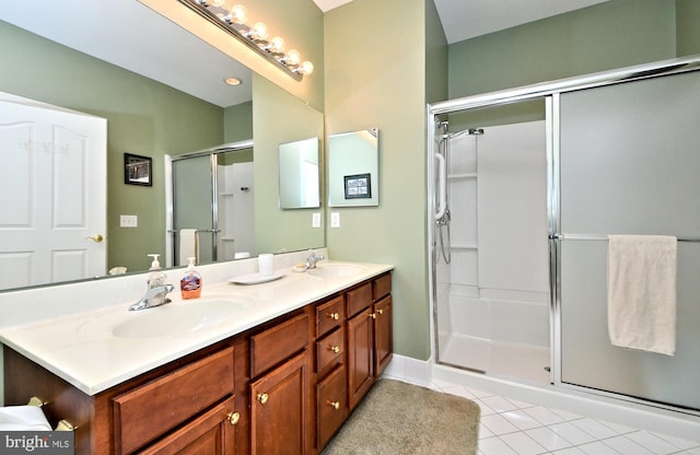 full bath with a shower stall, double vanity, a sink, and tile patterned floors