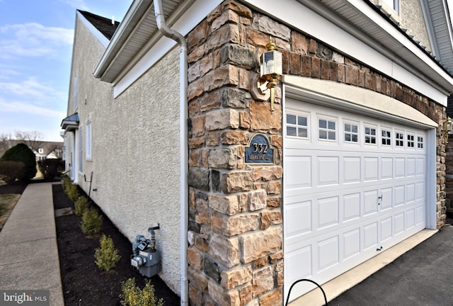 view of property exterior with a garage, stone siding, and stucco siding