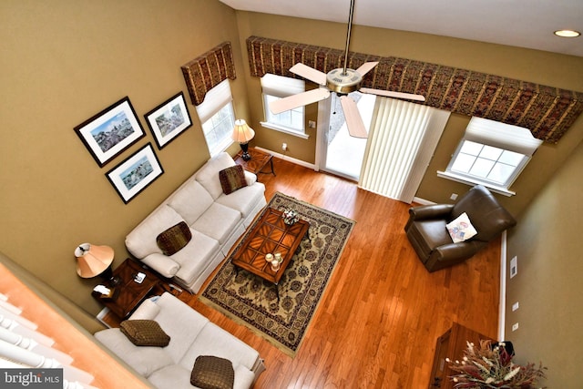 living area with a ceiling fan, baseboards, and wood finished floors