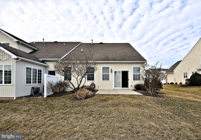 rear view of house featuring a patio area, a shingled roof, and a lawn