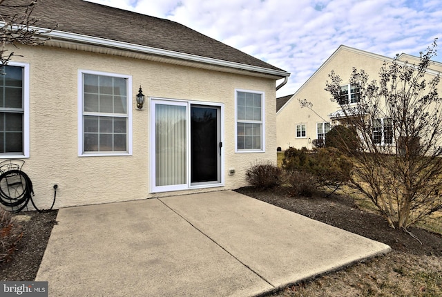 back of property with roof with shingles, a patio area, and stucco siding