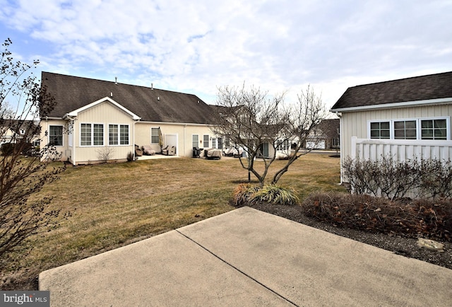 back of property featuring a yard, a shingled roof, and a patio area