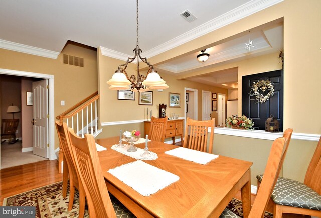 dining space featuring ornamental molding, visible vents, stairs, and wood finished floors