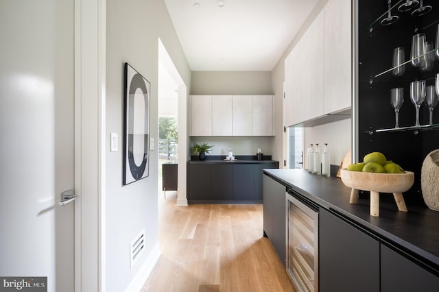 kitchen featuring light wood-style floors, dark countertops, modern cabinets, and wine cooler