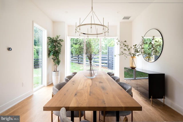 dining room with baseboards, light wood-type flooring, visible vents, and a healthy amount of sunlight