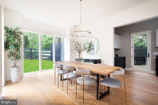 dining space featuring baseboards, an inviting chandelier, visible vents, and light wood-style floors