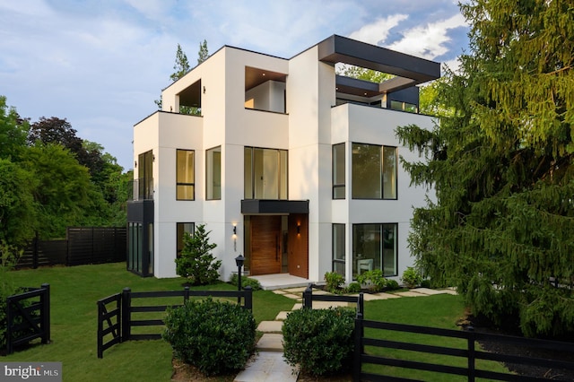 view of front facade with a fenced front yard, a balcony, a front lawn, and stucco siding