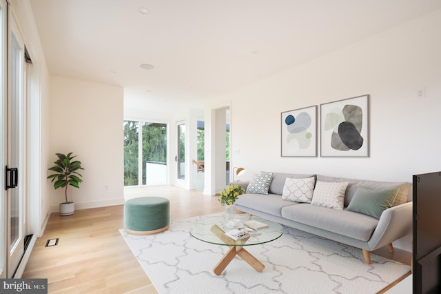 living area with light wood-style floors, visible vents, and baseboards