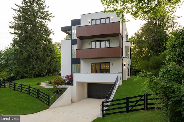 view of front of home featuring concrete driveway, a front lawn, fence, and stucco siding