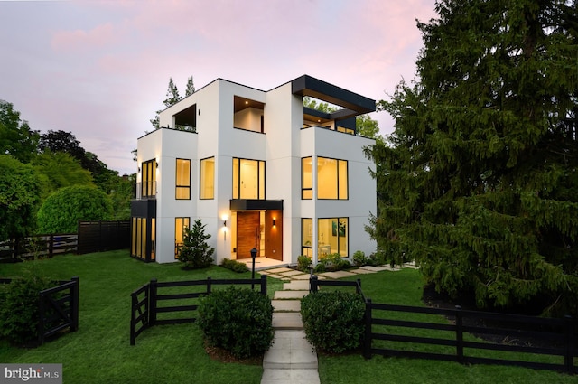 contemporary home with a yard, fence, a balcony, and stucco siding