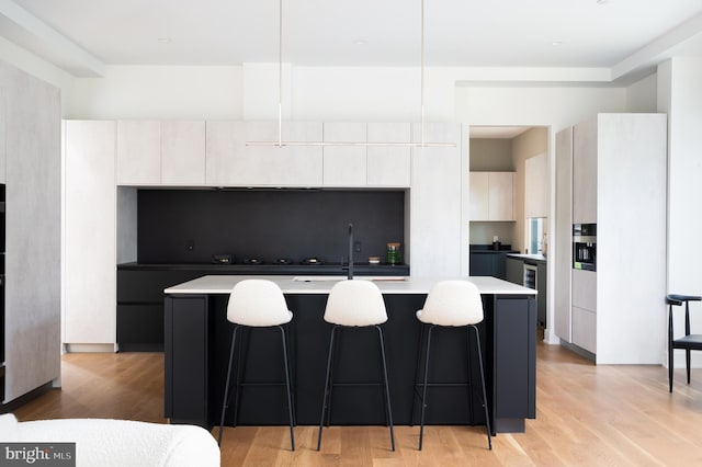 kitchen featuring an island with sink, modern cabinets, a sink, and a kitchen bar