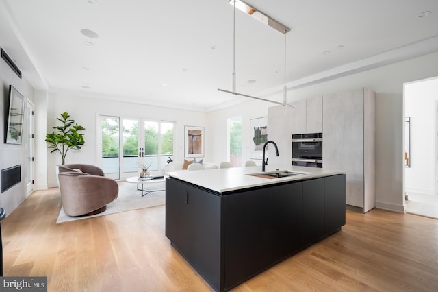 kitchen featuring light countertops, dobule oven black, light wood-style floors, a sink, and modern cabinets