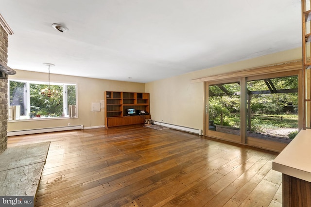 unfurnished living room with baseboards, a baseboard radiator, wood-type flooring, and a notable chandelier