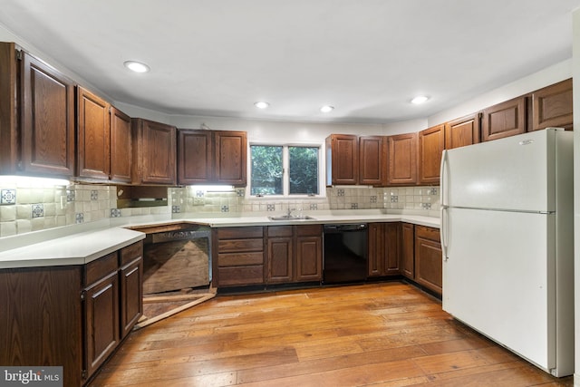 kitchen with light wood-style flooring, light countertops, dishwasher, and freestanding refrigerator