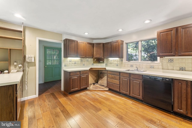 kitchen with a sink, light wood-style floors, light countertops, dishwasher, and tasteful backsplash