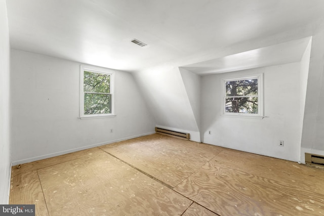 unfurnished room featuring visible vents, a baseboard heating unit, and vaulted ceiling