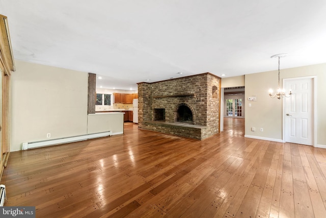 unfurnished living room with a chandelier, a baseboard radiator, a fireplace, baseboards, and light wood-style floors