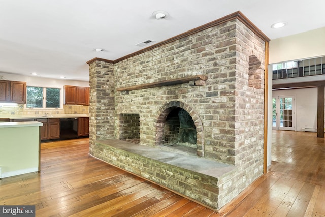 unfurnished living room featuring visible vents, a baseboard radiator, light wood-style flooring, a fireplace, and recessed lighting