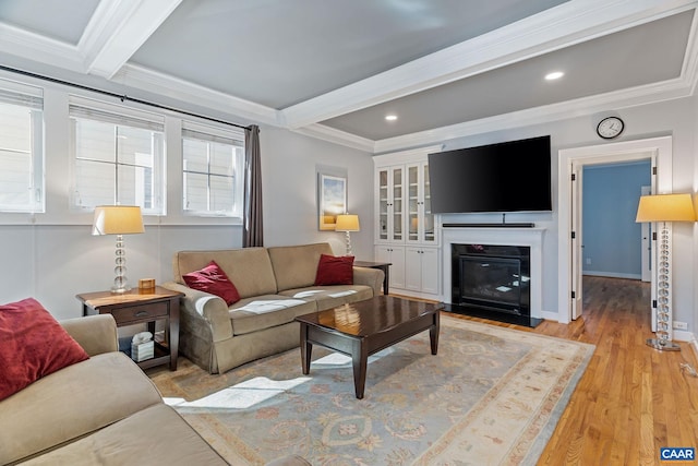 living room with ornamental molding, beamed ceiling, and light wood-style floors