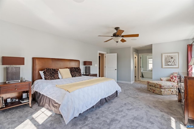 bedroom featuring light carpet, ceiling fan, ensuite bathroom, and baseboards