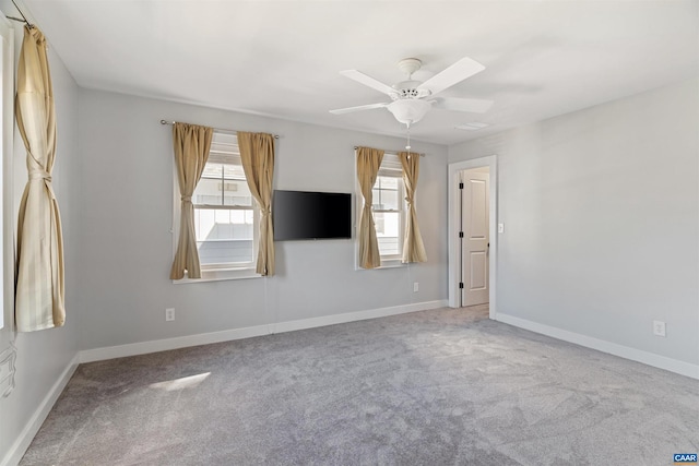 carpeted spare room featuring ceiling fan, plenty of natural light, and baseboards