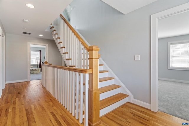 stairs featuring a healthy amount of sunlight, baseboards, and wood finished floors