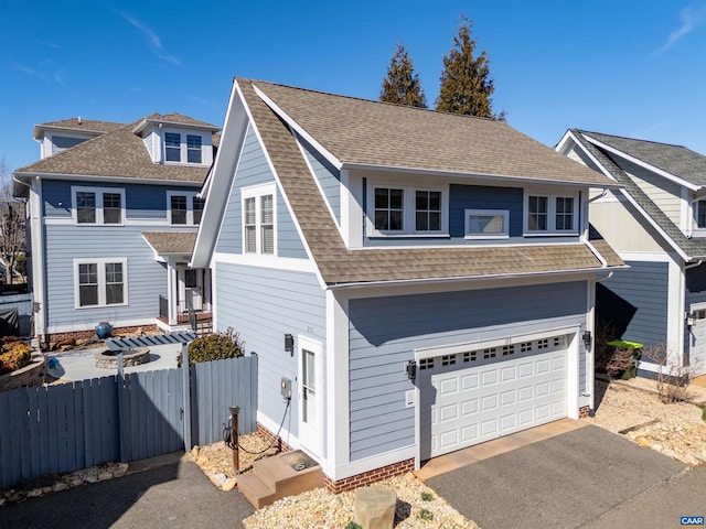 view of front of home with driveway, a shingled roof, an attached garage, and fence