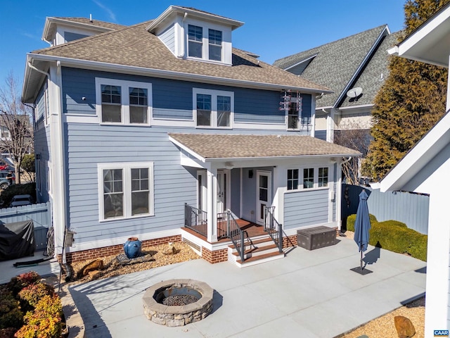 view of front of house with a fire pit, a patio, roof with shingles, and fence