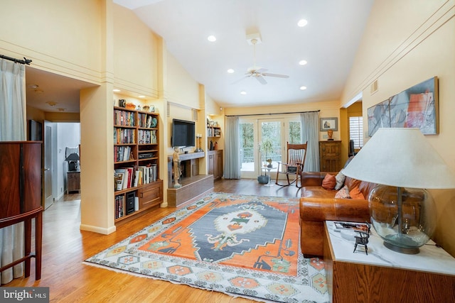 living room with a fireplace with raised hearth, high vaulted ceiling, recessed lighting, wood finished floors, and visible vents