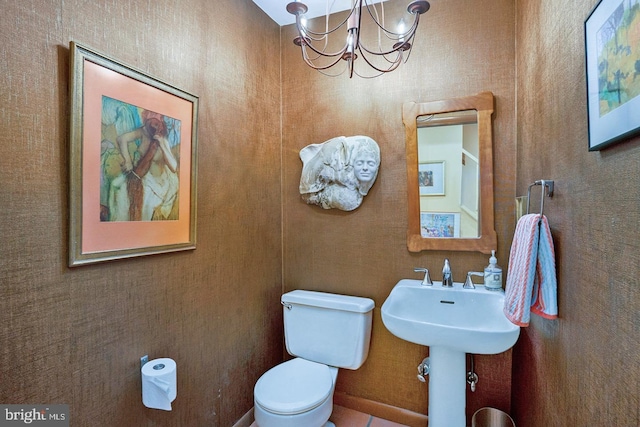 bathroom with toilet and a notable chandelier