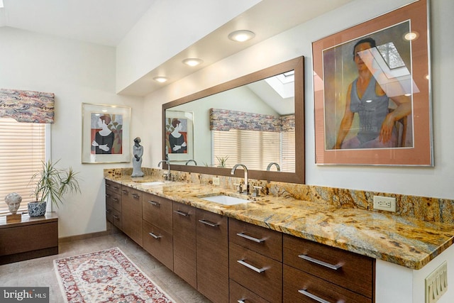 full bathroom featuring lofted ceiling with skylight, baseboards, and vanity