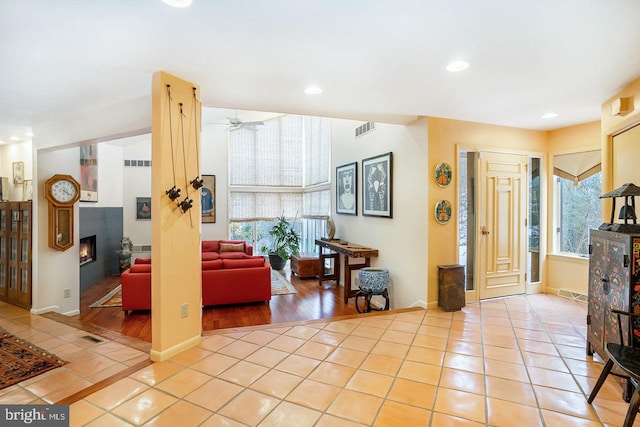 interior space with a wealth of natural light, a warm lit fireplace, visible vents, and recessed lighting