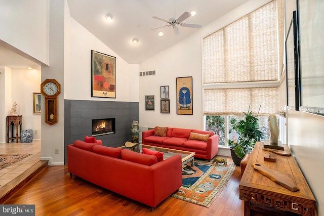 living area featuring high vaulted ceiling, recessed lighting, visible vents, hardwood / wood-style floors, and a tiled fireplace