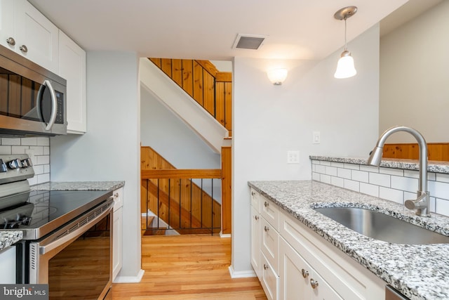 kitchen featuring light wood-style flooring, a sink, visible vents, white cabinetry, and appliances with stainless steel finishes