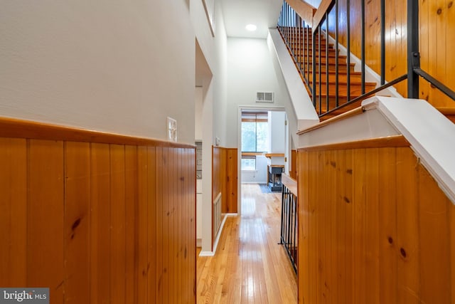 staircase featuring visible vents, wainscoting, hardwood / wood-style flooring, and wooden walls