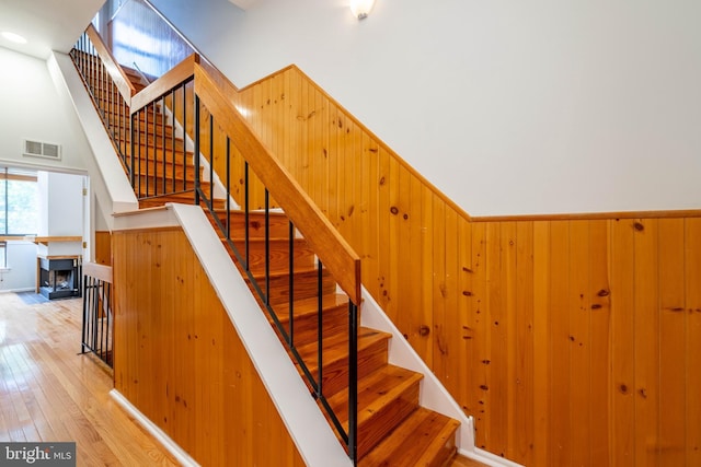 stairs with wood walls, wood-type flooring, and visible vents