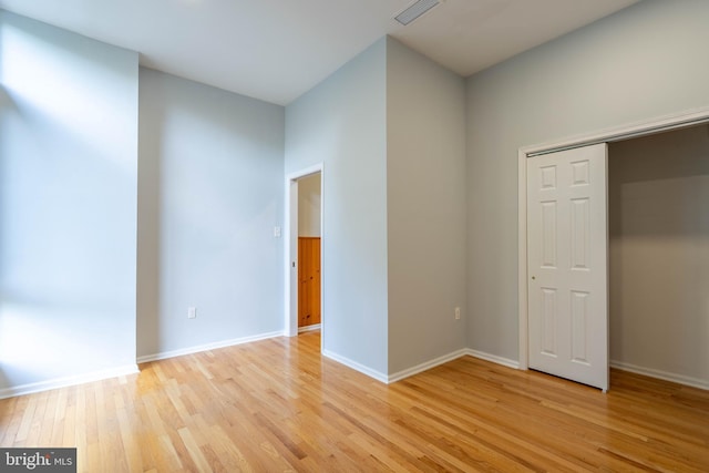 unfurnished bedroom with light wood-style floors, baseboards, visible vents, and a closet