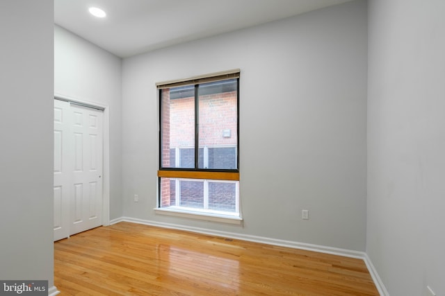 spare room featuring light wood finished floors, recessed lighting, and baseboards