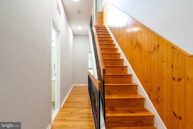 stairs featuring wood walls, visible vents, and wood finished floors